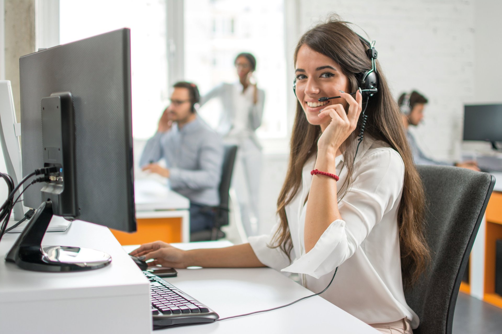 Eine Frau sitzt mit einem Headset am Computer