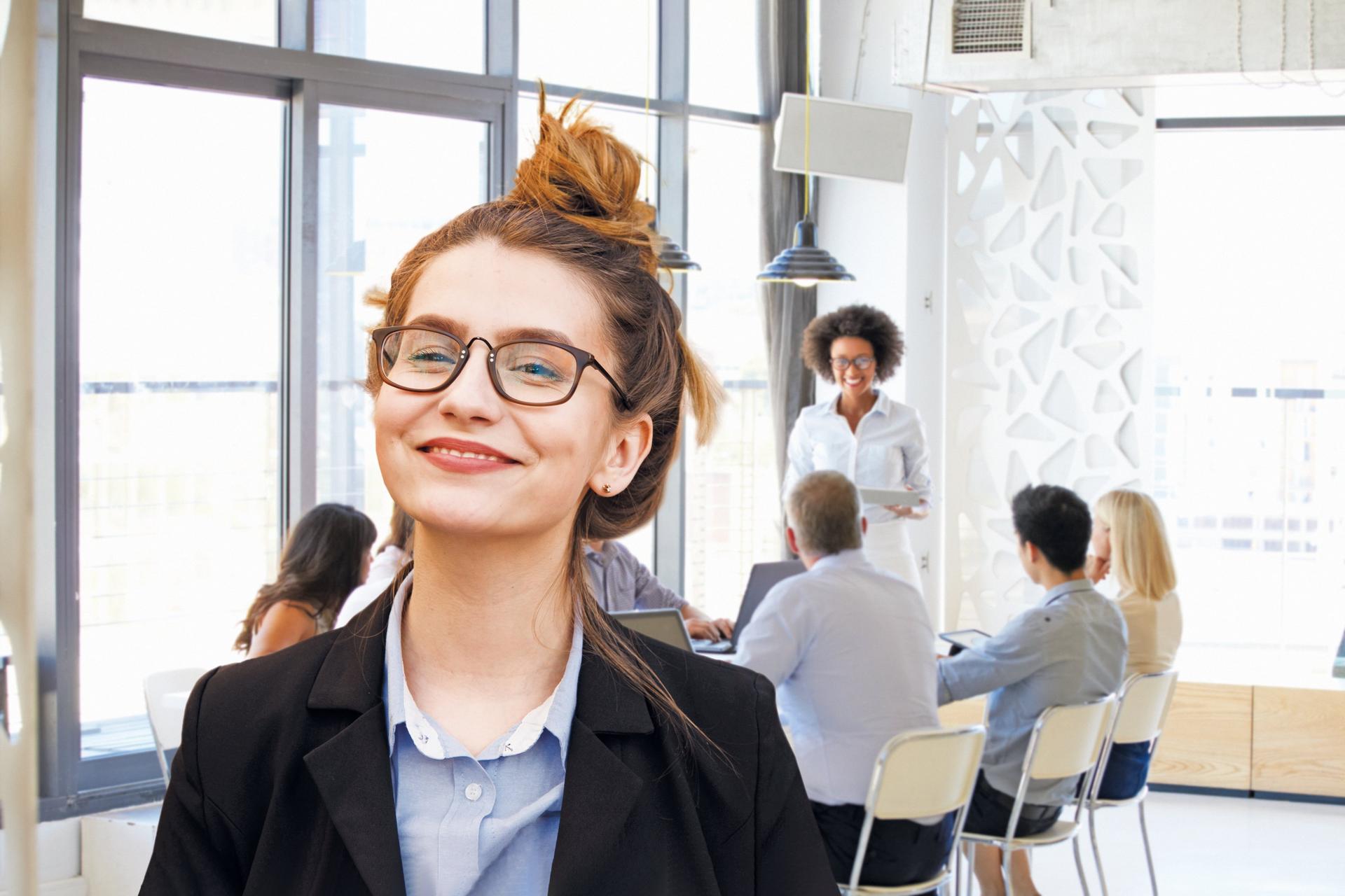 Frau im Vordergrund, im Hintergrund Konferenztisch mit Menschewn 