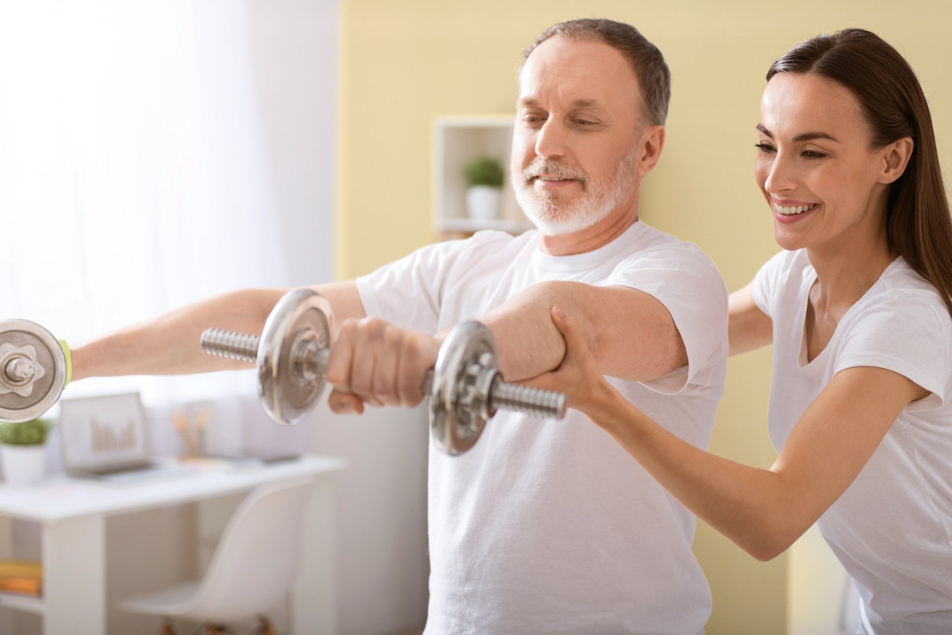 eine Physiotherapeutin mit einem Herrn beim Krafttraining