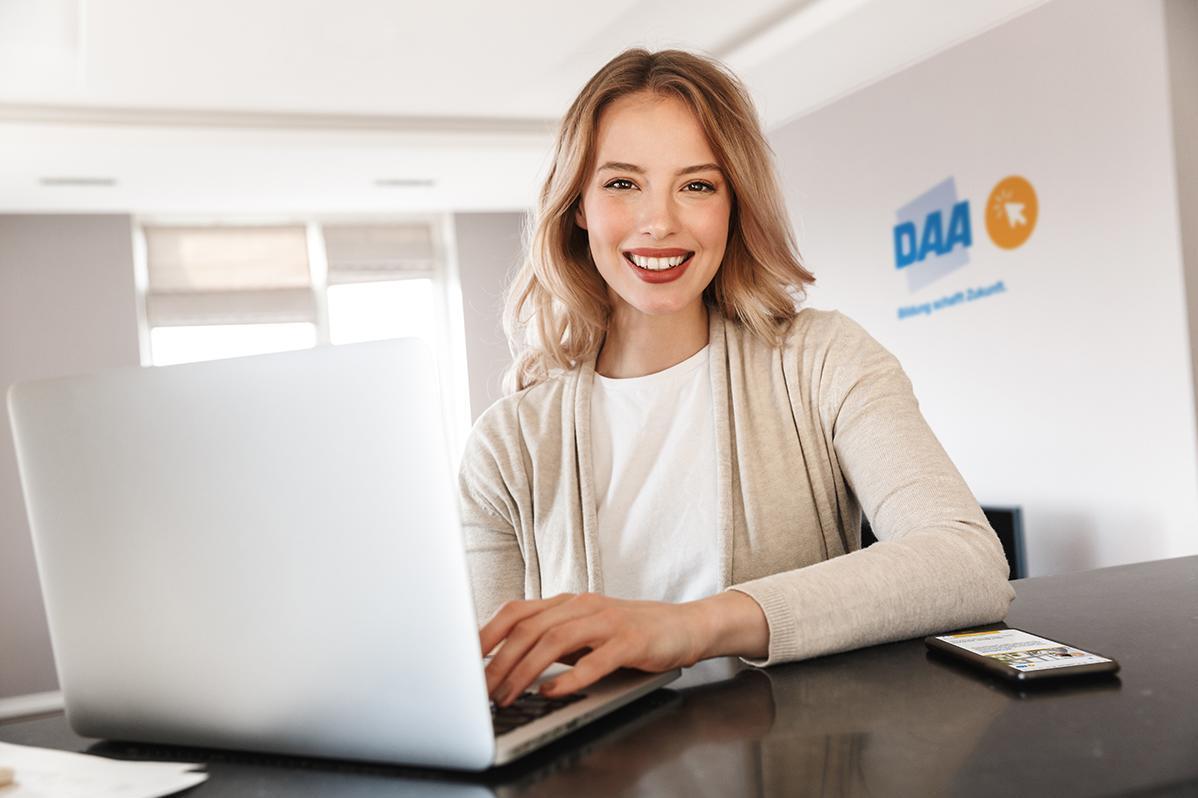 Eine blonde Frau nimmt am Laptop an einer Online-Weiterbildung teil