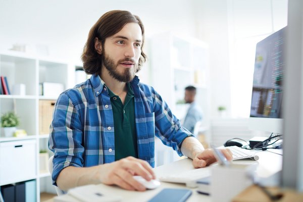 ein junger Mann arbeitet in einem Büro an einem Computer