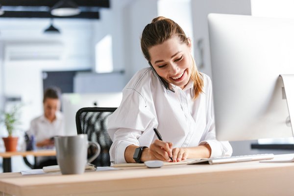 eine Büroangestellte in einem Büro macht sich während eines Telefonats Notizen