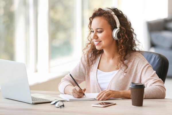 eine Kauffrau mit Headset telefoniert und macht sich Notizen