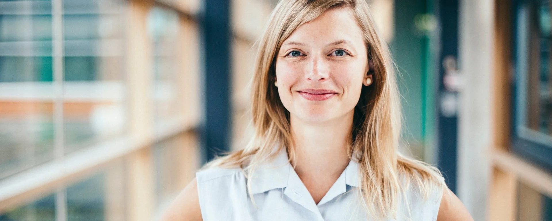 eine blonde, junge Frau lächelt freundlich