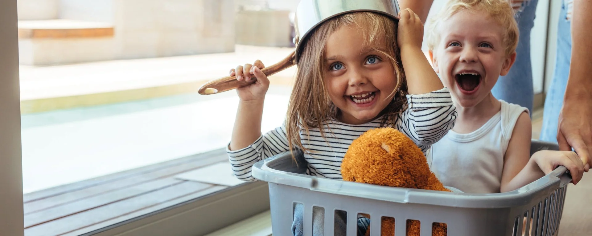 zwei Kinder spielen in einem Wäschekorb