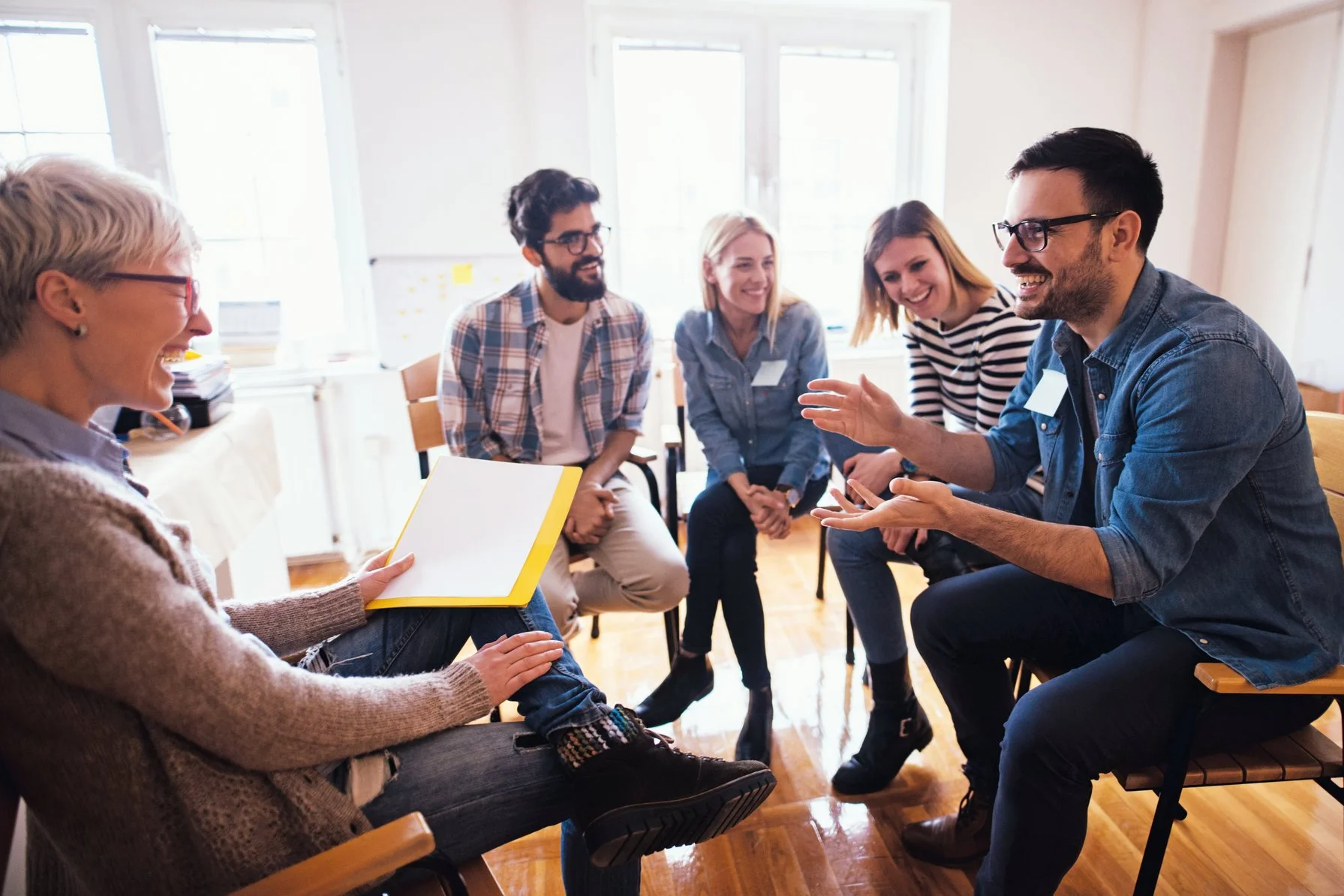 Fünf Personen haben Spaß in einem Gruppencoaching
